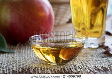 Apple cider vinegar in a glass bowl with an apple in the background