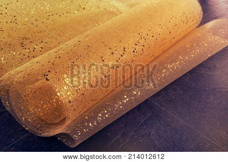Gold Thread And Gliters On The Fabric Texture. Textile Roll With Waves And Wrinkles On The Dark Cosm