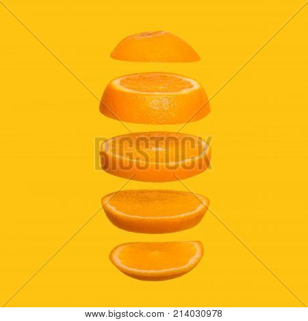 Creative concept with flying orange. Sliced orange on yellow background. Levity fruit floating in the air