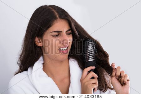Beautiful Woman In Bathrobe Brushing Her Curly Hair At Home