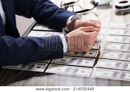 Businessperson In Handcuffs Arrested For Bribe With American Banknotes On Desk
