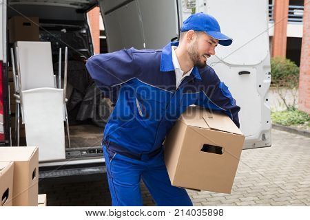 Young Male Worker Carrying Cardboard Box Suffering From Backpain