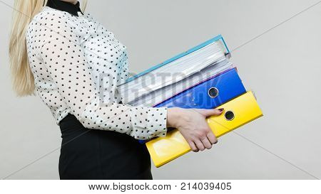 Woman holding many heavy colorful binders with documents. Office bookkeeping objects concept.