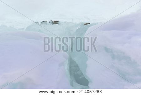 Transparent blue ice hummocks on lake Baikal shore. Siberia winter blur background. Snow-covered ice of the lake