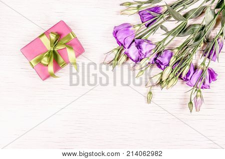Pink gift box and flowers on a white wooden background. Mothers Day.