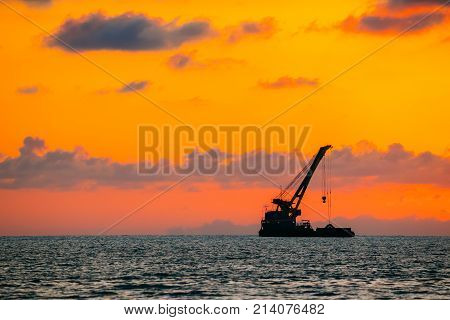Sundown Over Sea Horizon At Sunset. Dark Silhouette Of Fishing Boat At Horizon Of Seascape. Natural Sunrise Sky Warm Colors Over Ocean.