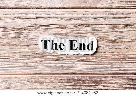 The End of the word on paper. concept. Words of The End on a wooden background.