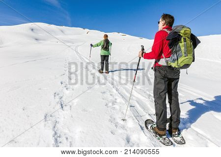 Two hikers with snowshoes in winter mountain landscape. Alps in Germany, Bavaria, Allgau.