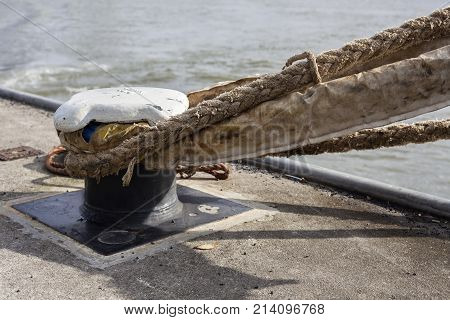 Thick boat ropes tied to an old rusty bollard
