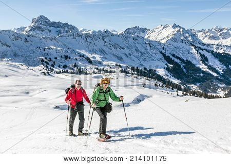 Mature couple hiking with snowshoes in winter mountain landscape. Alps, Germany, Bavaria, Allgau.