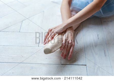 Closeup of young ballerina legs in pointe shoes at white wooden floor background, with copy space. Ballet practice. Beautiful slim graceful ballet dancer.