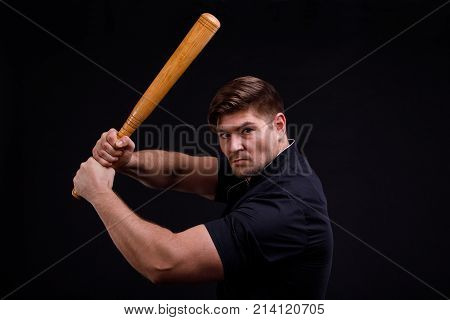 A man swings a bat standing sideways and a confident look on a black background