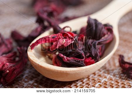 Petals Of Tea On A Wooden Spoon Close-up. Macro Photo Of Red Petals Of Sudanese Rose, Hibiscus Flowe