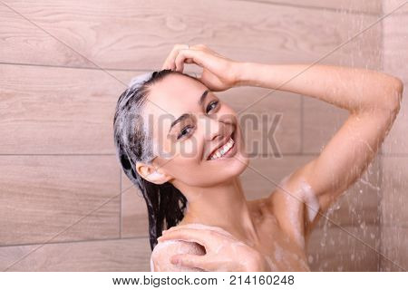 Young beautyful woman under shower in bathroom.