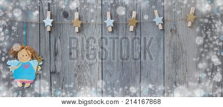 Decorated clothespins hanging on the rope with a little christmas fairy and snow around fraime.
