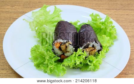 Japanese Cuisine Traditional Vagetarian Japanese Rice Maki Sushi Roll Stuff with Tofu and Carrot Wrapped in Nori Seaweed Served on Green Oak.