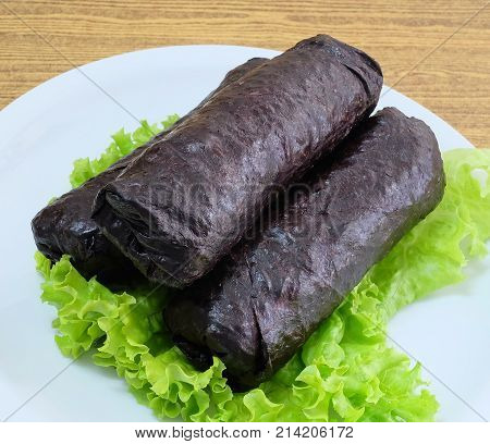 Japanese Cuisine Traditional Unsliced Japanese Rice Maki Sushi Roll with Nori Seaweed Served on Green Oak.
