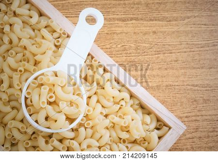 Food and Cuisine Uncooked and Dried Elbow Macaroni or Gomiti Pasta in Plastic Measuring Cup.