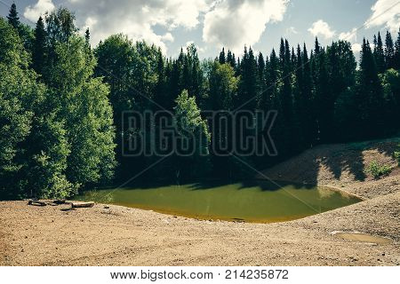 A place for camping on a green lake surrounded by forest.