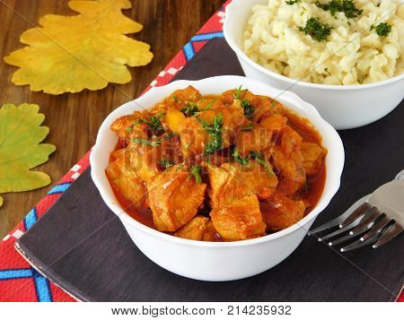Meat stewed in tomato sauce. Porkolt, Hungarian cuisine meal. Nokedli, a type of egg noodle in the background
