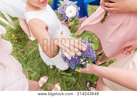 Little sweet girlfriend of the bride brags her ringlet to her adult friends with her hand on the bouquet on the exit registration