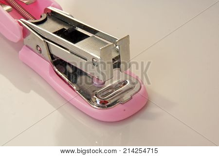 Pink colored stapler tool. Pink colored office tool.