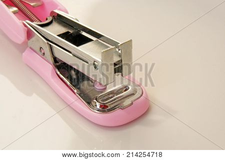 Pink colored stapler tool. Pink colored office tool.