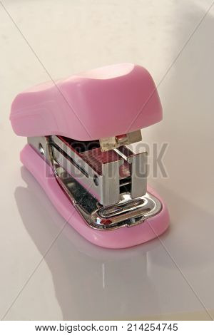 Pink colored stapler tool. Pink colored office tool.
