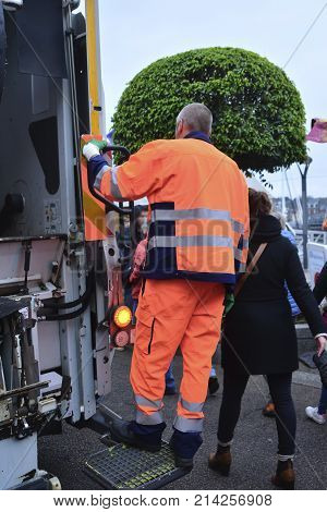 garbage collector rides on a garbage truck on the street