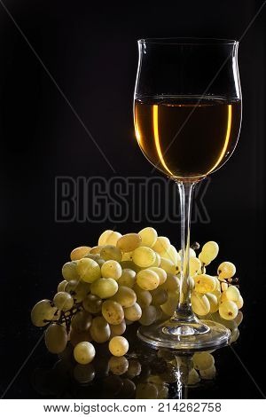 Glass of wine and a bunch of grape on a studio glass background