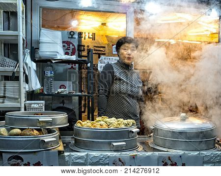 dongmun market jeju south korea - 4th november 2017: traditional mandu street vendor at her steam filled stall at dongmun market
