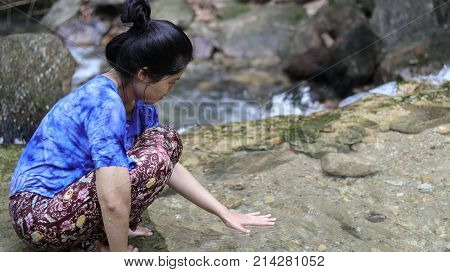 Woman playing Hands on water in a waterfall.