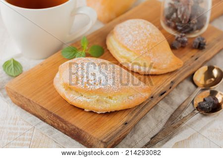 Pasties with cottage cheese and powdered sugar on a light wooden background. Traditional Russian pastry Sochnik. Selective focus. .