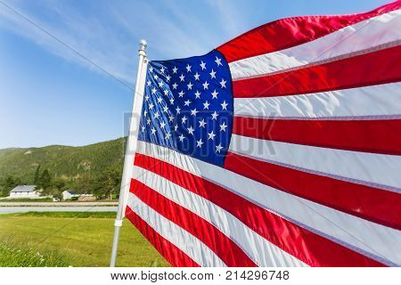 Flag of the United States of America (American flag or The Stars and Stripes Old Glory The Star-Spangled Banner) waving in the wind against summer forest landscape in sunny day.
