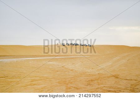 Group of off-roadster cars on sand hill. Car tour of the Sahara desert. Tunisia.