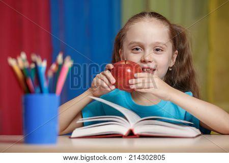 Portrait Of Happy Pretty Girl Holding A Red Apple In The Classroom