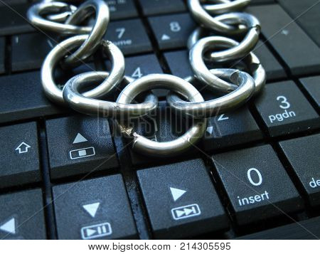Chain on computer keyboard. It means laptop banned or internet banned. Symbol of computer addiction, games, social networks, block chain for crypto currency and so on