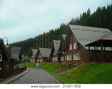Wooden cottages are at mountain resort near forest under blue sky