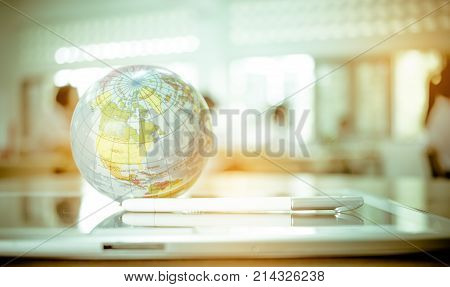 Earth globe model ball map with class room background on tablet in classroom. Concept for global international educaiton or communications politics environmental for learning world wide. vintage tone