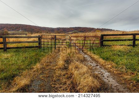 A gate blocks entry to a muddy primitive dirt road that appears less traveled.