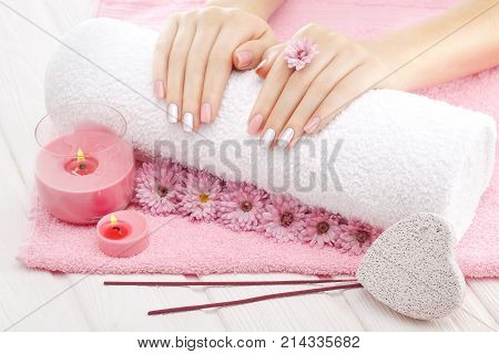 beautiful pinc manicure with candles, chrysanthemum flower and towel on the white wooden table. spa