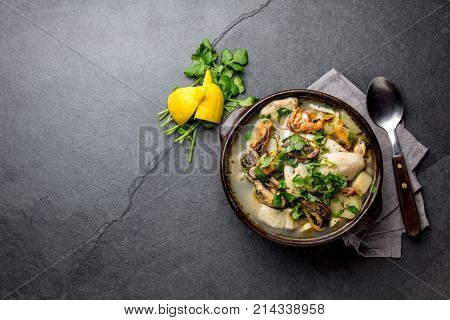 Seafood Soup in clay bowl on gray slate background.