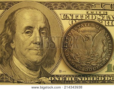 One hundred US banknote and vintage one dollar Morgan coin. Antique and modern money to make profit and income. Closeup macro symbol of economy, finance and investment.