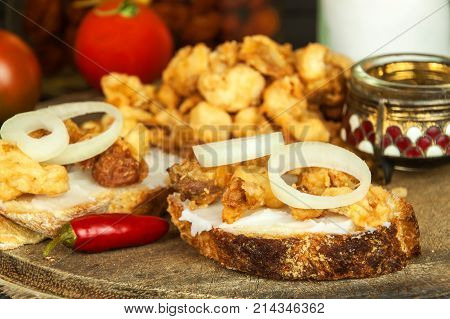 Heap of domestic salty fried pork greaves. Fatty junk food. Pork greaves on the kitchen board