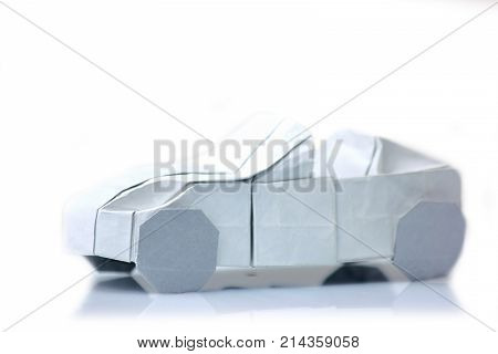 Origami car model on white. Vehicle figurine made of folded paper. Art exposition item.