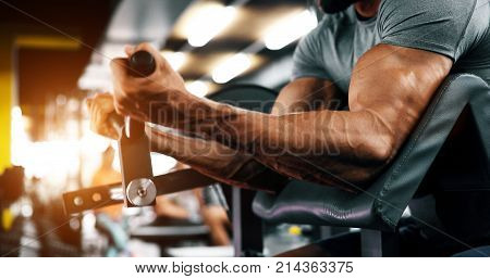 Muscular bodybuilder guy doing exercises with dumbbells in gym