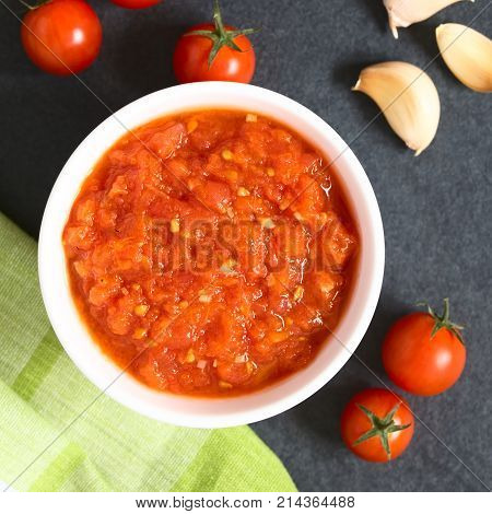 Homemade traditional Italian marinara or pomodoro tomato sauce made of fresh tomato garlic dried oregano and salt served in bowl with ingredients on the side photographed overhead on slate with natural light (Selective Focus Focus on the top of the sauce)