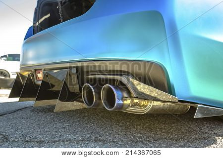 Dual Exhaust Pipes On A Custom Car With Rear Spikes And Teal Paint