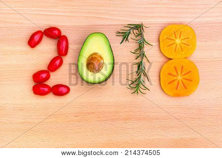 Happy new year 2018 made of vegetables herbs and fruits on wooden background.