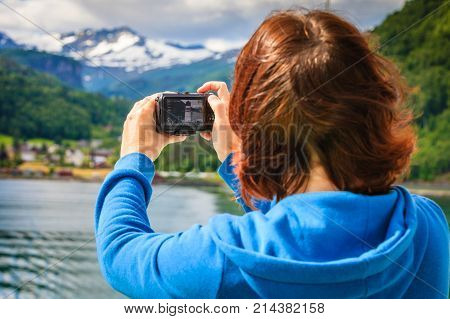 Tourism vacation and travel. Tourist woman on cruise ship enjoying fjord view taking photo with camera. Norway Scandinavia Europe. Norddalsfjorden as seen from ferry.